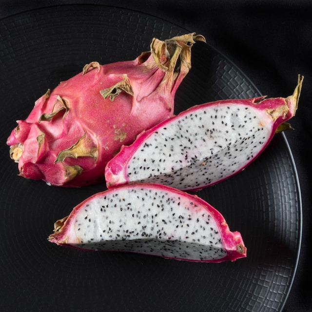Slices of dragon fruit on a black plate
