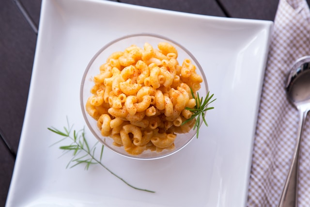 A bowl of macaroni and cheese on a white ceramic square plate