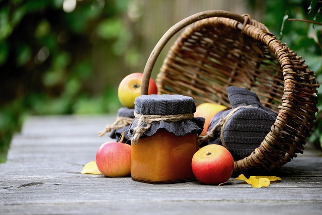 A jar of jam surrounded by apples spilling from a woven basket