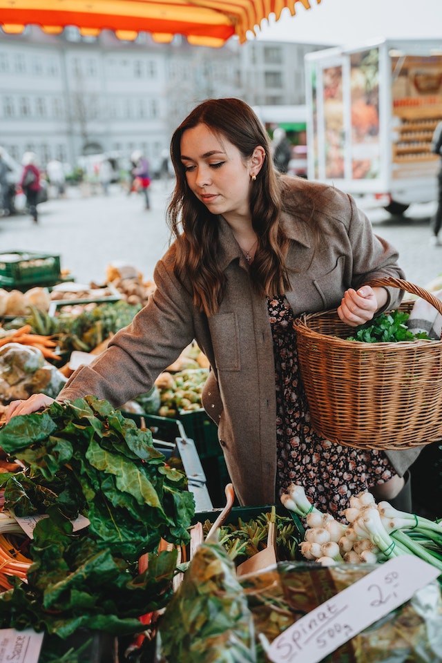 A woman carrying a basket while shopping at a farmers market