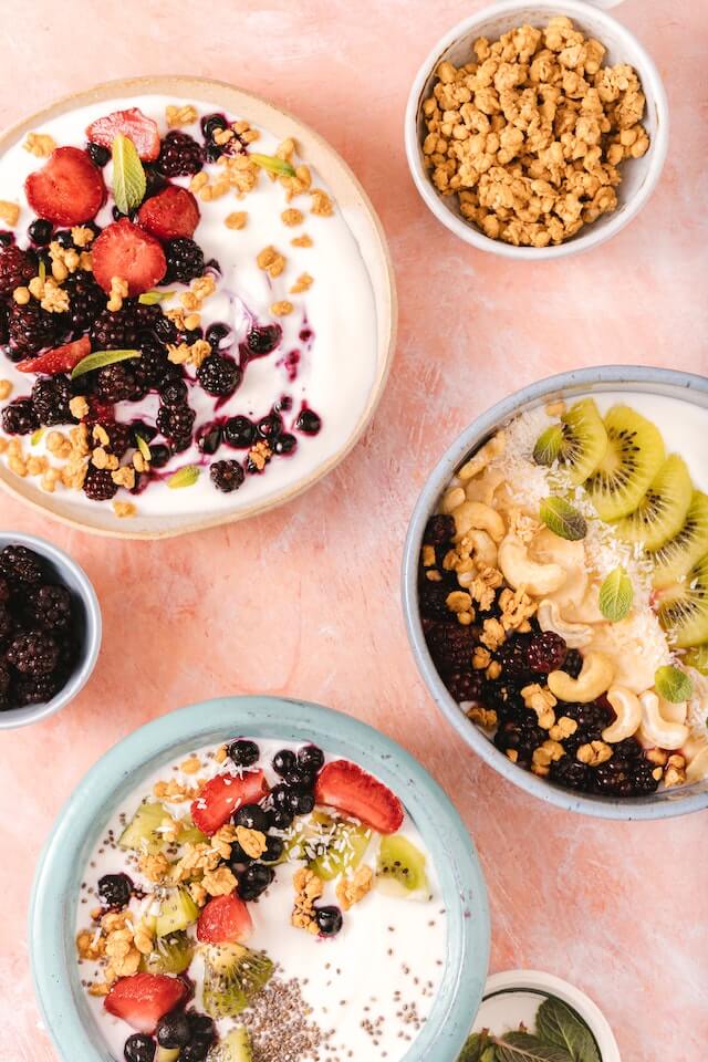 Smoothie bowls topped with varieties of fruits, seeds, and nuts
