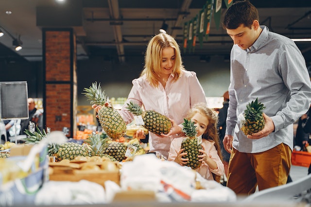 Family checking out the pineapples at a supermarket