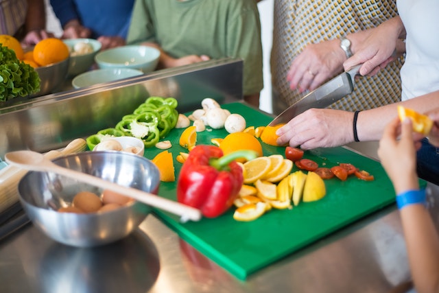 Person chopping fruits and vegetables on a green chopping board
