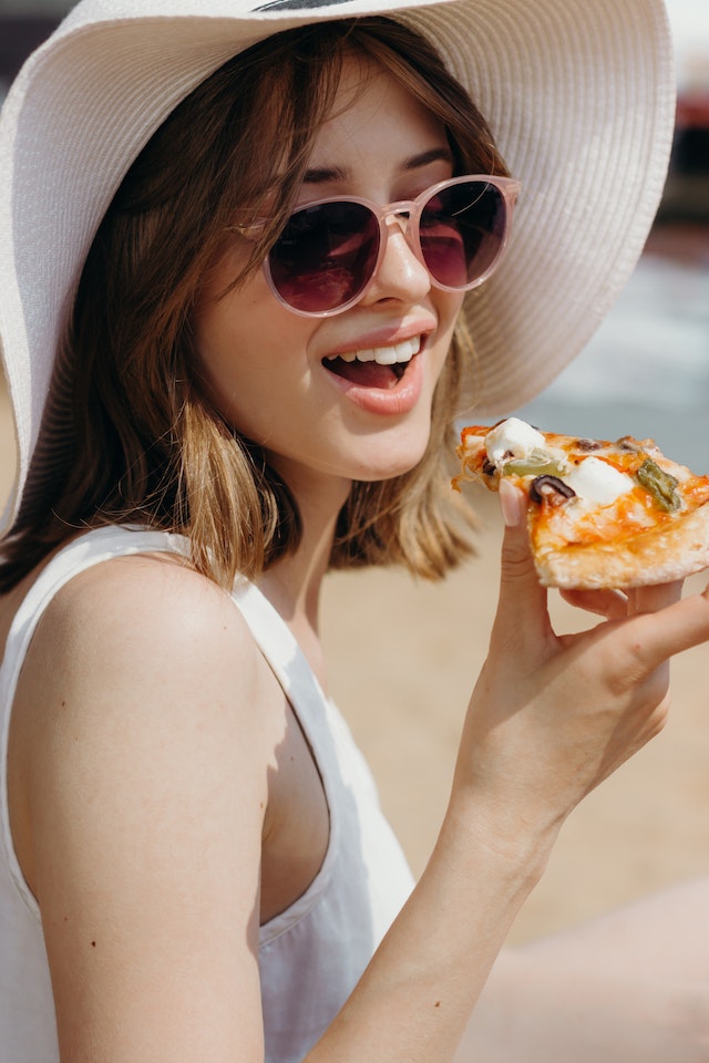 A woman holding a slice of pizza