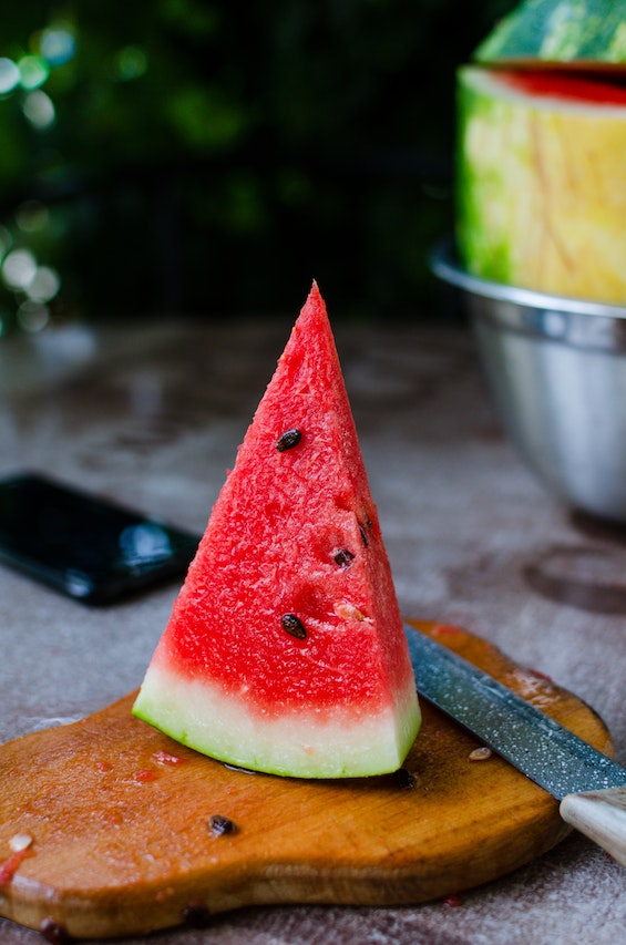 A slice of watermelon on a wooden chopping board 