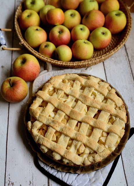 A baked apple pie with fresh apples on the side
