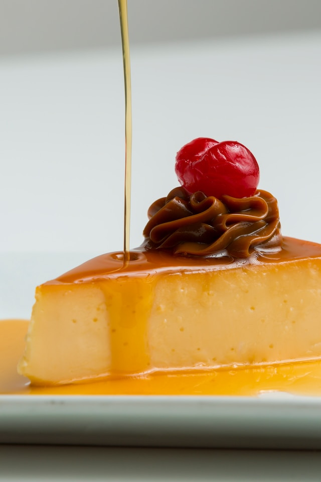 A slice of flan topped with caramel and cherries
