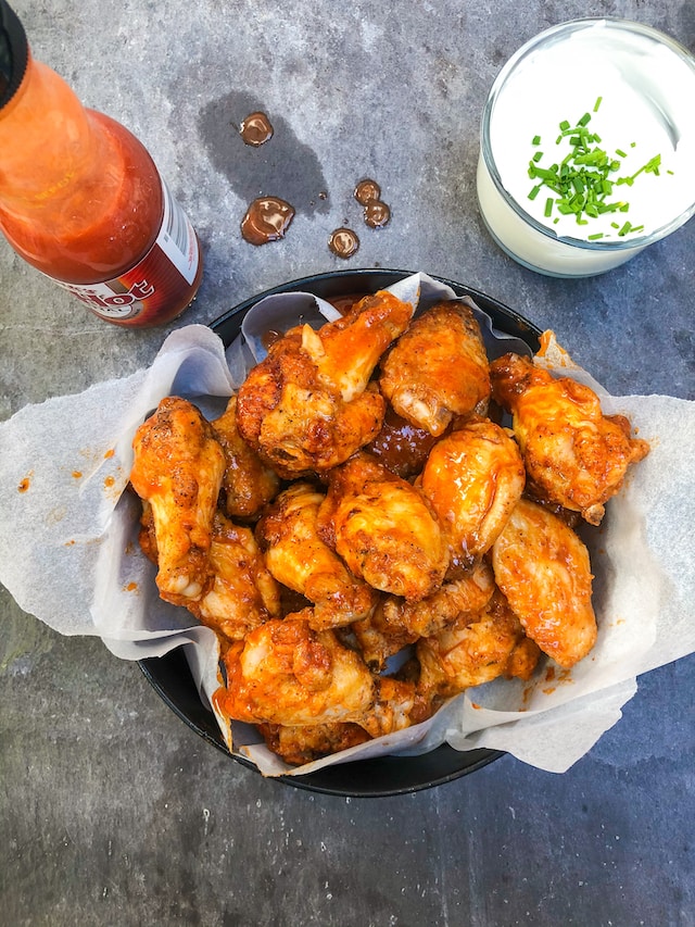 Chicken wings coated in hot sauce served with a white dipping sauce