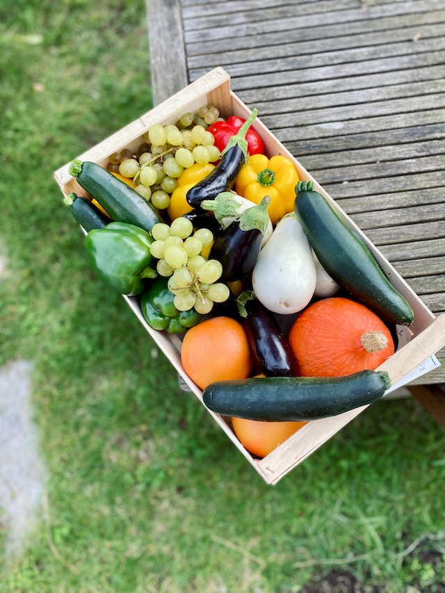 An assortment of fruits and vegetables inside a wooden crate