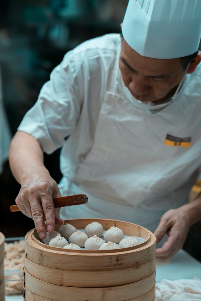 A chef arranging dumplings inside a bamboo steamer