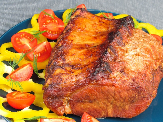 Roasted meat served with cherry tomatoes, yellow bell pepper slices, and dill