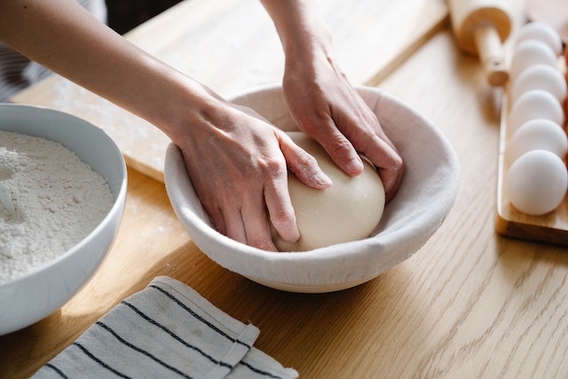 Person adding bread dough to a proofing bowl