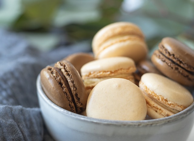 Cream and brown colored macarons in a ceramic bowl