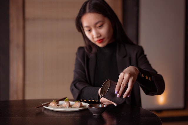 Woman pouring some dipping sauce into a tiny bowl