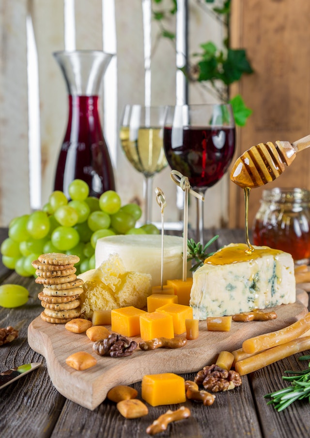Assorted cheese, wine, nuts, and fruits on a table