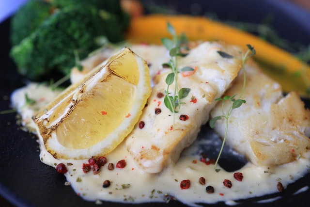 Creamy fish dish topped with a wedge of lemon and some thyme