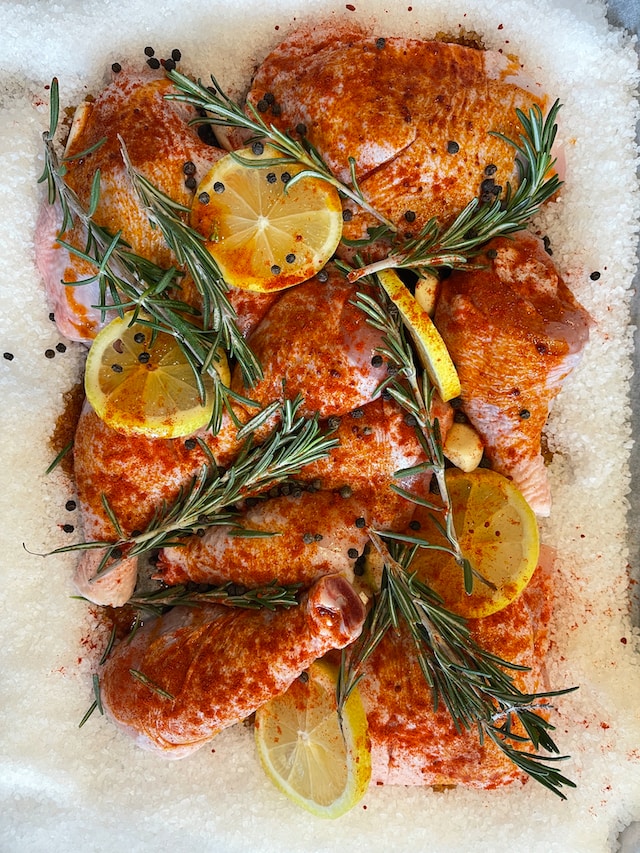 Seasoned chicken drumsticks with lemon slices and topped with sprigs of rosemary