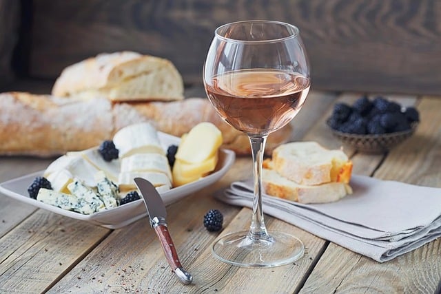 Assorted cheese, bread and a glass of pink wine on a table0