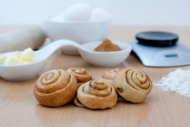 Cinnamon buns on a table with assorted baking ingredients