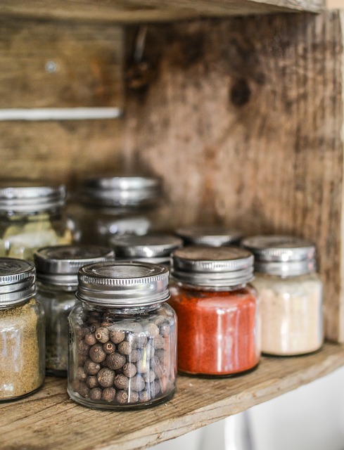 An assorted of spices inside small glass jars on a shelf